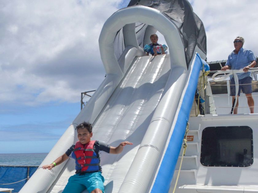 Kids playing on a floatable slide on board