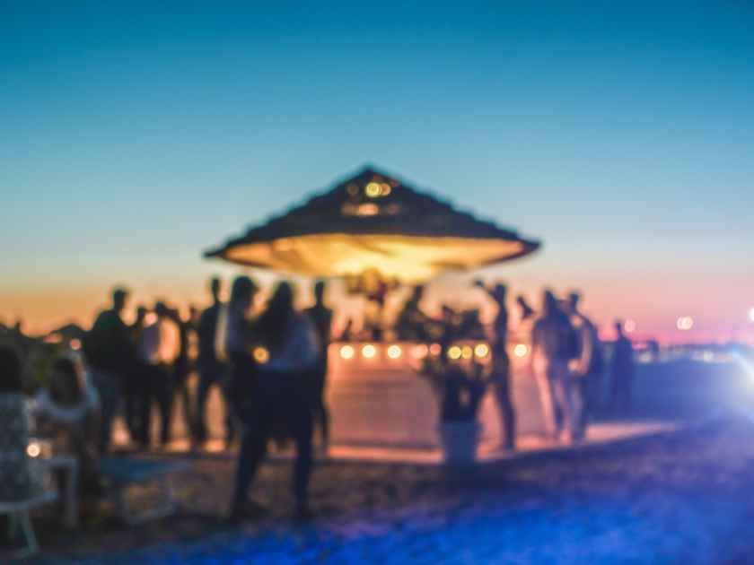 Blurred people having sunset beach party in summer vacation - Defocused image - Concept of nightlife with cocktails and music entertainment