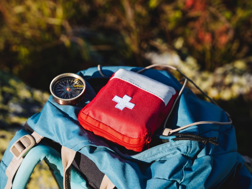 Compass first aid kit are in a backpack, a navigator in the taiga, a first aid kit in emergency situations, a white cross, medicines in a red bag. High quality photo