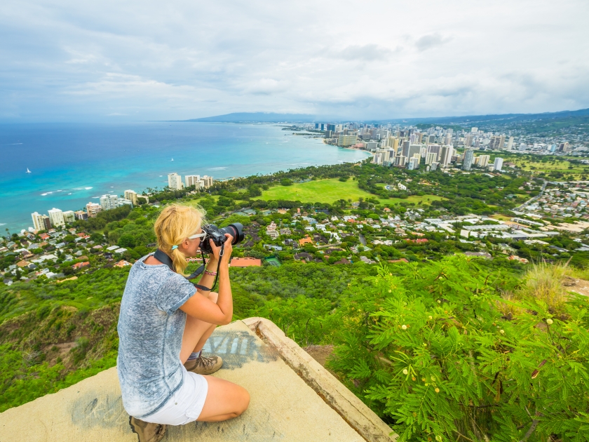 Travel photographer takes a shot of Honolulu and Waikiki beach, Oahu in Hawaii from Diamond Head State Monument. Nature photographer taking pictures outdoors during hawaiian hiking Diamond Head hike.