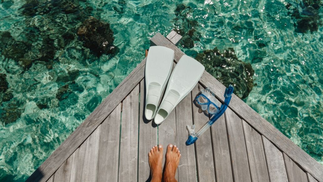 Beach vacation snorkel girl snorkeling with mask and fins. Equipment for snorkeling. Woman legs on wooden pier with snorkeling equipment