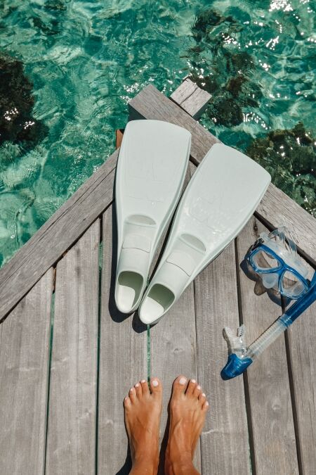 Beach vacation snorkel girl snorkeling with mask and fins. Equipment for snorkeling. Woman legs on wooden pier with snorkeling equipment