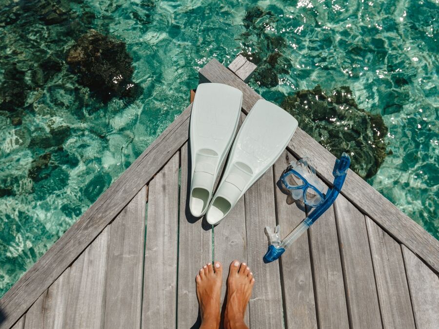Beach vacation snorkel girl snorkeling with mask and fins. Equipment for snorkeling. Woman legs on wooden pier with snorkeling equipment