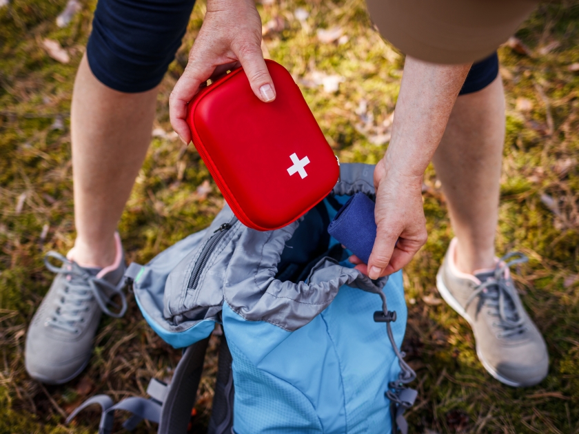 Woman taking out first aid kit from backpack. Prepared for health problems during hiking. Travel insurance for all eventualities