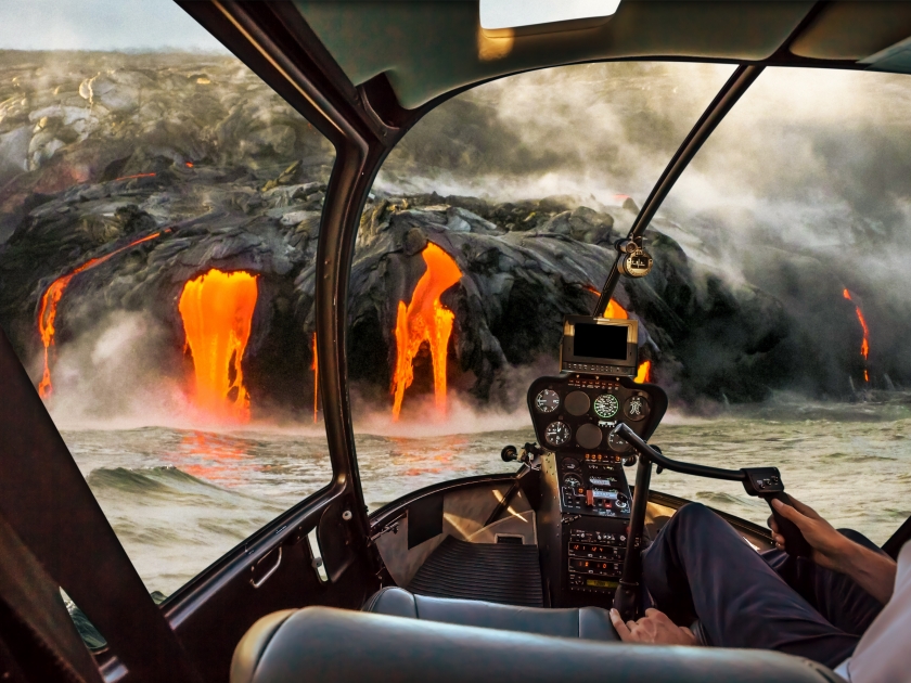 Helicopter cockpit flies in Kilauea Volcano, Big Island, Hawaii, United States by sunset, with pilot arm and control board inside the cabin.