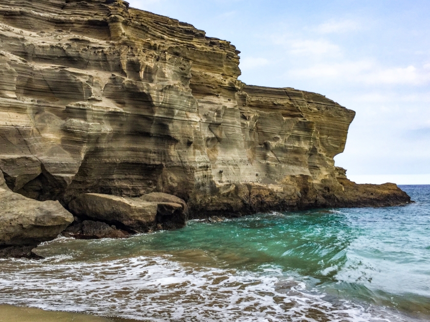 Majestic layered rock cliff formation by the ocean at Papakōlea Beach, Hawaii