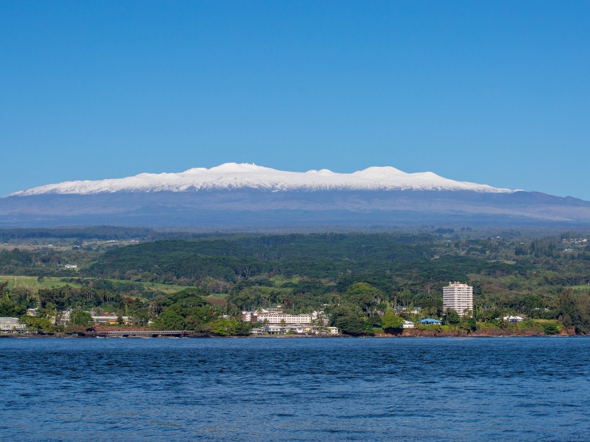 Picture of Hilo, Hawaii on a sunny day with snow-capped Mauna Kea in the backgroundl