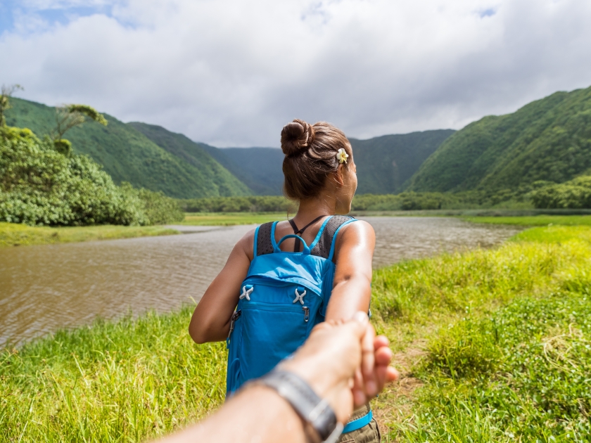 Hawaii travel nature hiker follow me woman hiking in Pololu valley holding hand of boyfriend following leading girlfriend walking. Big island destination, woman tourist in Hawaii, USA.