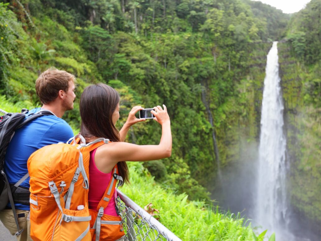 Couple,Tourists,On,Hawaii,By,Waterfall.,Tourist,Taking,Photo,Pictures