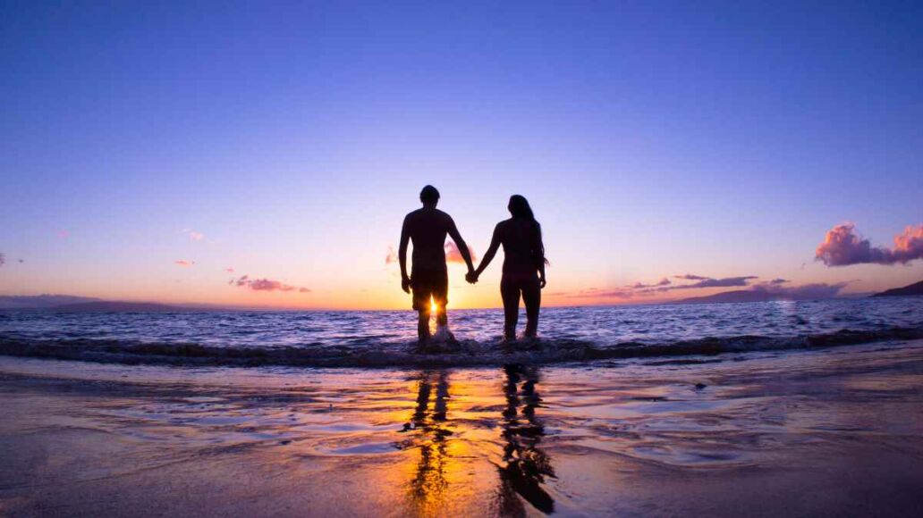 Romantic couple enjoying a beach walk at sunset