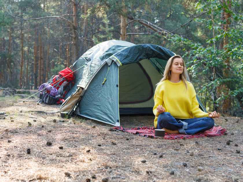 Breath with the morning forest and free your mind with meditation. Young woman is meditating in a morning pine forest. Solitude with your thoughts and nature. Nature as a path to mental health.