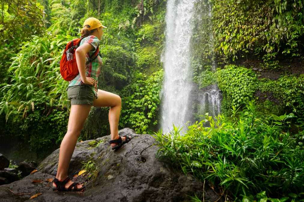 Young woman backpacker looking at the waterfall in jungles.