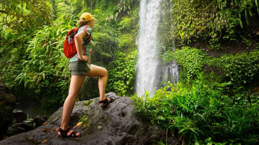 Young woman backpacker looking at the waterfall in jungles.
