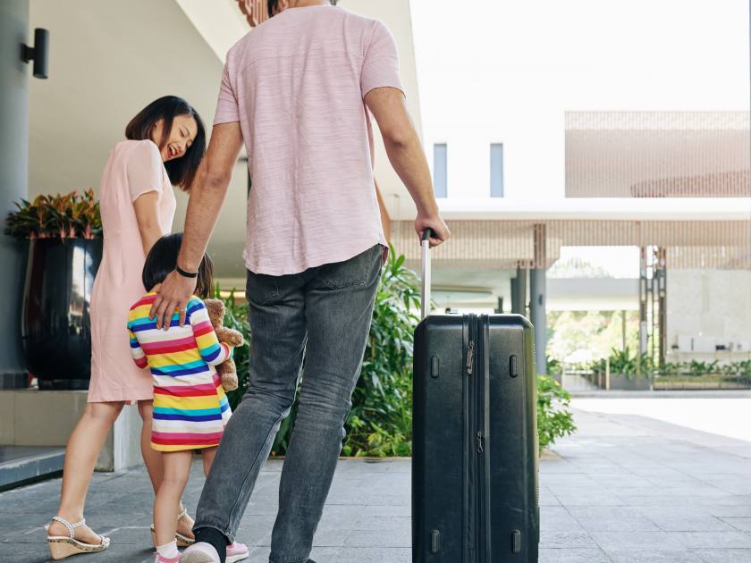 Happy Asian family with big suitcase leaving hotel andfter staying for some days