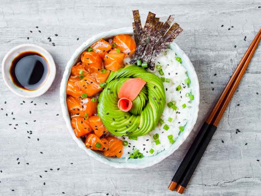 Hawaiian salmon poke bowl with seaweed, avocado rose, sesame seeds and scallions. Top view, overhead, flat lay