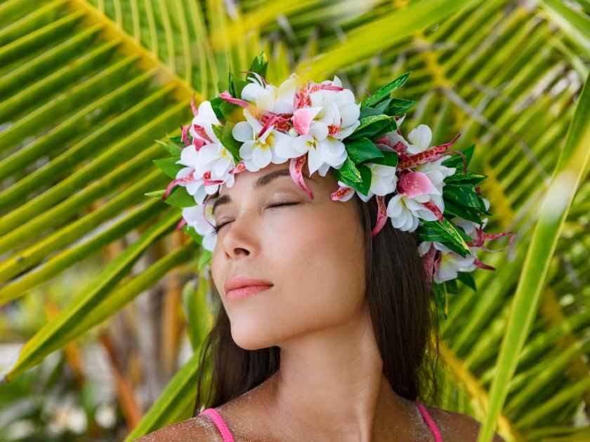 Exotic beauty wellness woman relaxing with closed eyes on tropical beach with Tahiti wreath of flowers hair accessory. Bora Bora, French Polynesia.