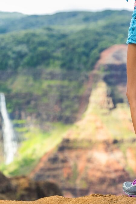 HIking hiker girl at Waimea Canyon Kauai looking at Waipoo falls Hawaii waterfall. Kauai travel.