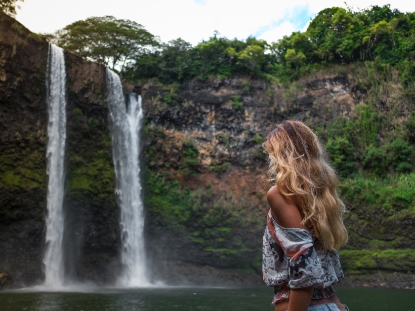 beautiful waterfall in Kauai Hawaii, back of sexy woman. Woman looks at waterfall. Young pretty woman enjoying waterfall view . Wailua Falls