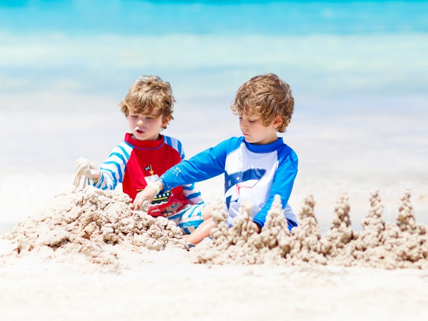 Two kid boys building sand castle on tropical beach of Boracay, Philippines