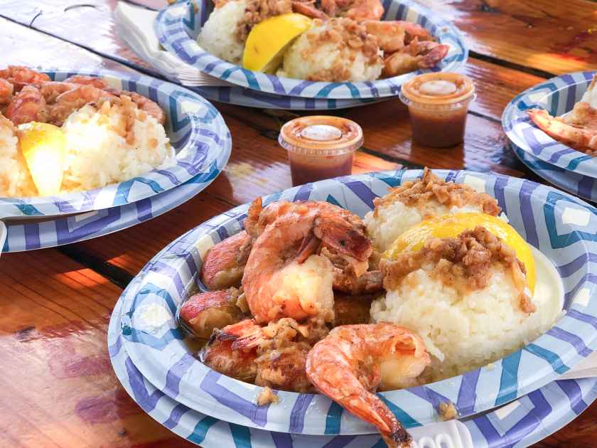Closeup of famous Hawaiian garlic shrimp and rice plate lunch. Plates with cooked shrimp, lemon, and garlic at Oahu's North Shore.