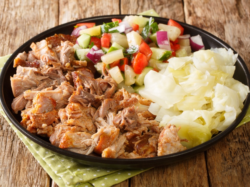 Hawaiian Kalua Pork with stewed cabbage and fresh salad close-up in a plate on the table. horizontal