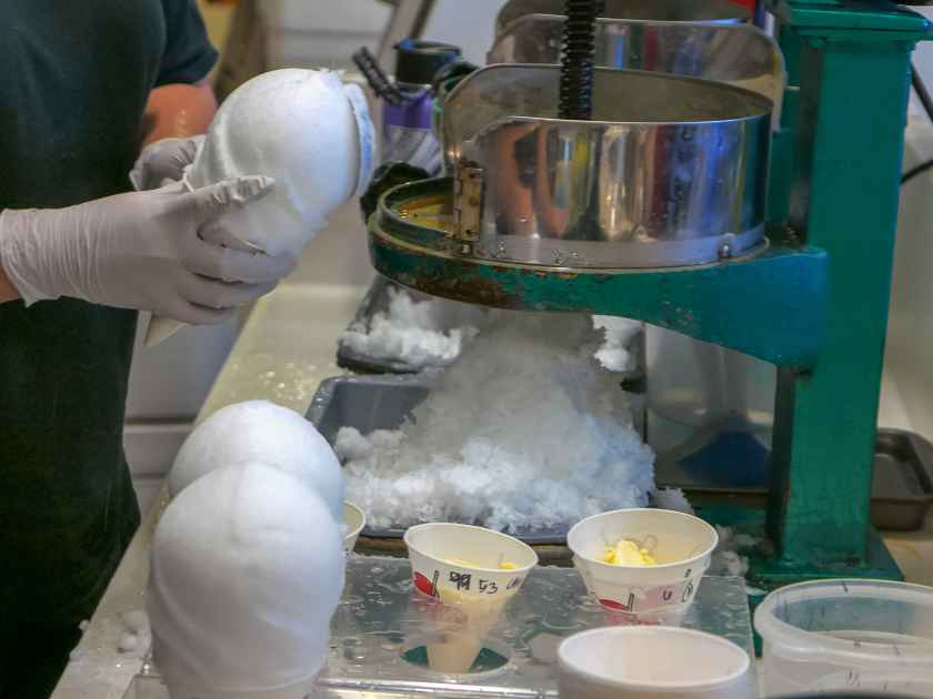 a shop assistant makes hawaiian shave ice cones