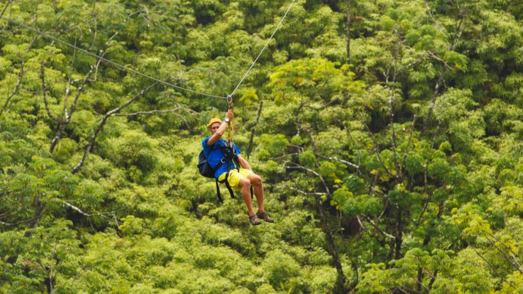 Man on Zipline over Lush Tropical Valley