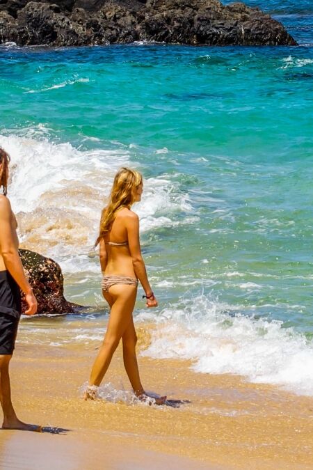 A couple enters the warm waters of the Pacific Ocean at Waimea Bay on the north shore of Oahu, Hawaii.