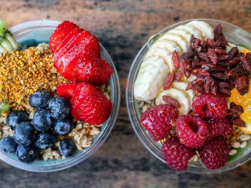 Acai bowls top view banner panoramic of healthy food breakfast smoothie bowl at restaurant. Two fruit cups filled with spirulina, kiwi, goji berries summer eating.