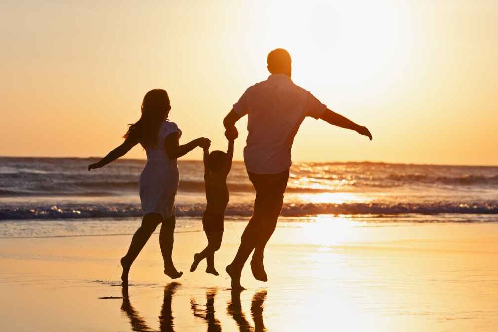 Happy family black silhouette on sun background. Father, mother, baby son run. Child jump with fun by water pool along sea surf on beach. Travel lifestyle, parents walking with kid on summer vacation.