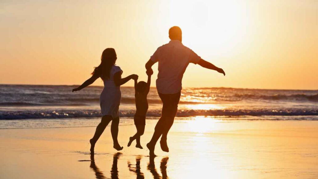 Happy family black silhouette on sun background. Father, mother, baby son run. Child jump with fun by water pool along sea surf on beach. Travel lifestyle, parents walking with kid on summer vacation.
