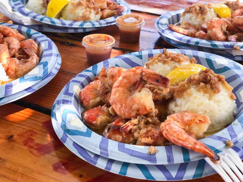Closeup of famous Hawaiian garlic shrimp and rice plate lunch. Plates with cooked shrimp, lemon, and garlic at Oahu's North Shore.