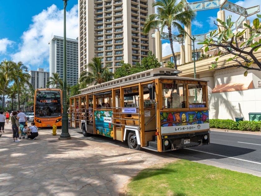Honolulu, Hawaii - March 31, 2019: The Waikiki Trolley bus on Kalakaua Avenue in Waikiki. Many tourist buses drive tourists around beautiful Honolulu and Oahu islands.