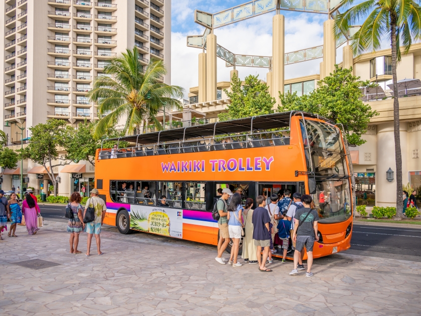 Honolulu, Hawaii - December 29, 2022: The Waikiki Trolley picking up tourists on Kalakaua Avenue.