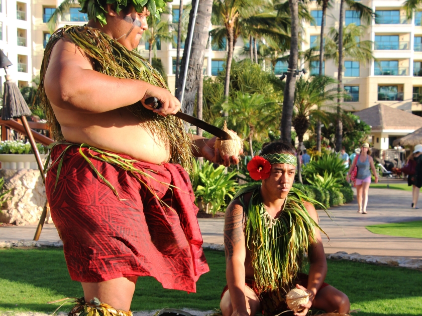 Hawaiian luau. A man in a traditional Hawaiian costume cutting a fresh picked coconut. Ko Olina, Oahu, Hawaii. The picture was taken in August 2015.