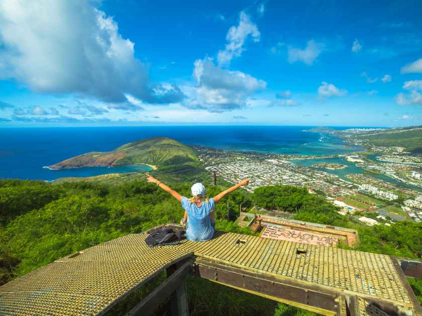 Happy woman enjoying at top of koko head Crater trail.Aerial view of Hanauma Bay, Diamond Head and Honolulu, Oahu, Hawaii, USA. Hawaiian hiking in nature scenic landscape.Female hiker with raised arms