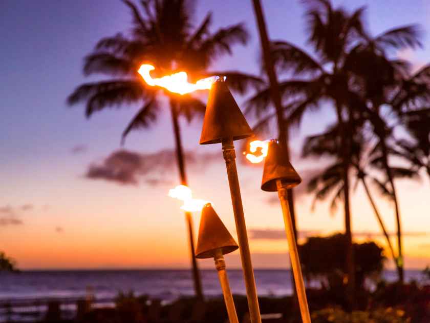 Hawaii sunset with fire torches. Hawaiian icon, lights burning at dusk at beach resort or restaurants for outdoor lighting and decoration, cozy atmosphere.