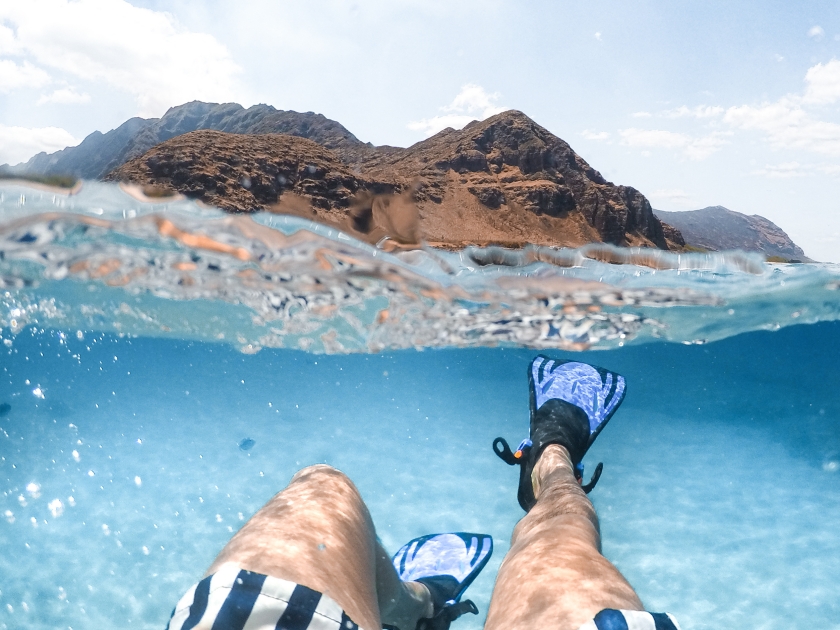 Snorkling in the turquoise blue water of Hawaii - oahu. Makua Beach. Swimming with the view to the mountain. Underwater shoot.