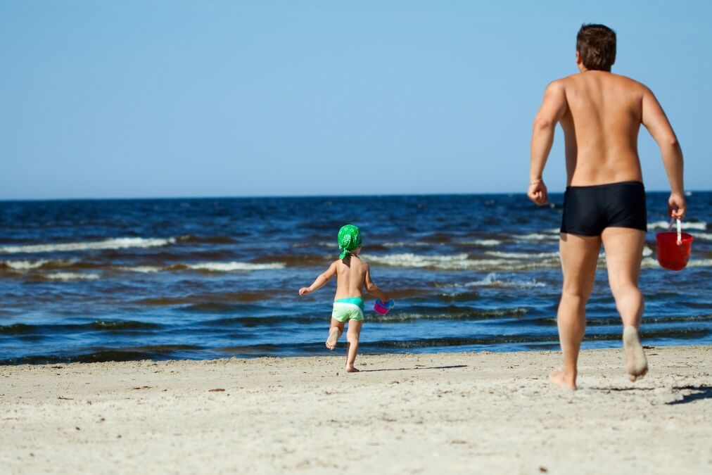 Family of two frolicking on the beach.Some parts in motion (they were running).