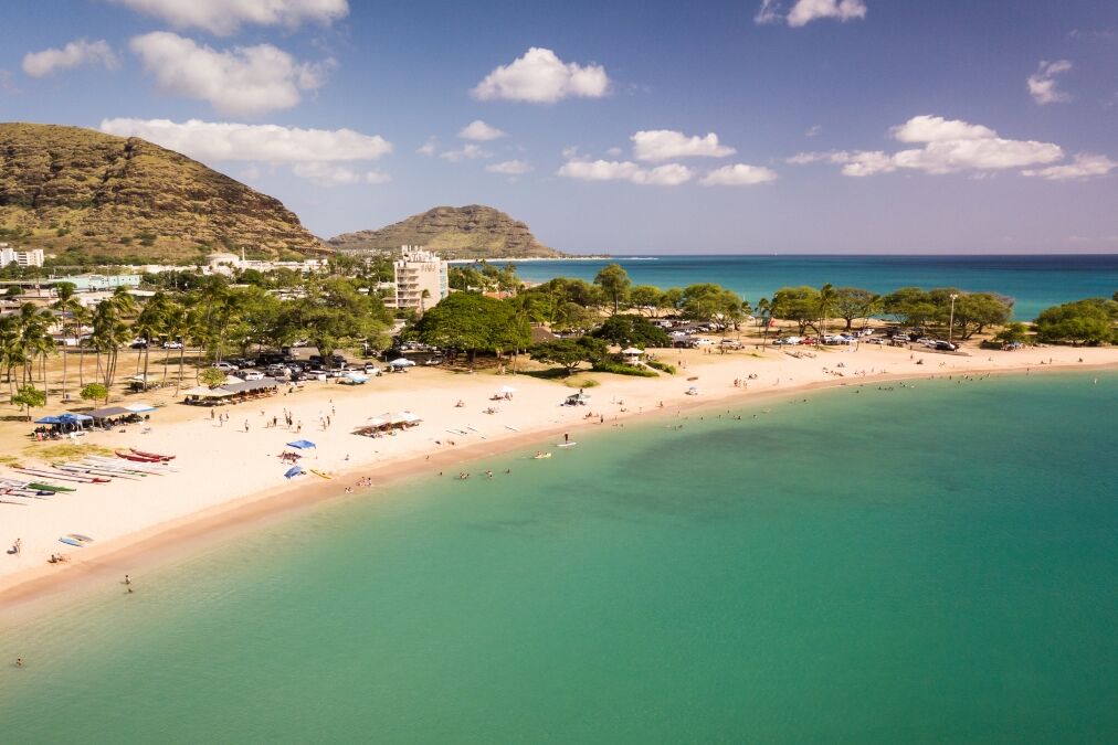 Beautiful aerial image of Pokai Bay beach park and seascape with the clear, blue, tropical waters washing along the shore.