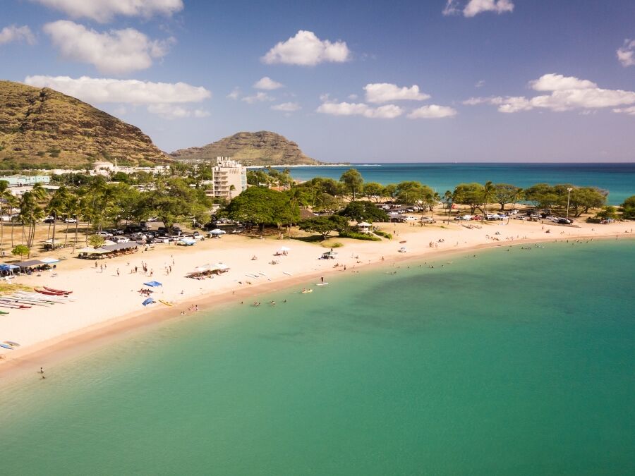 Beautiful aerial image of Pokai Bay beach park and seascape with the clear, blue, tropical waters washing along the shore.