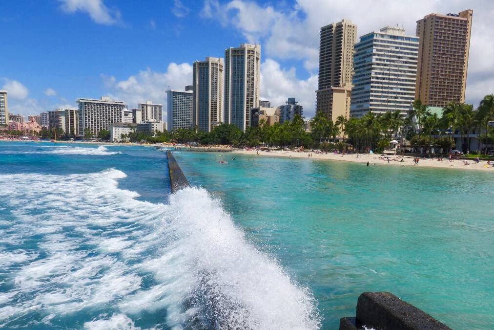 Wave Crashing on Breakwater Wall at Kuhio Beach Lagoon - View of Lagoon, Beach and Hotel Skyline - Waikiki Beach, Honolulu, Oahu, Hawaii