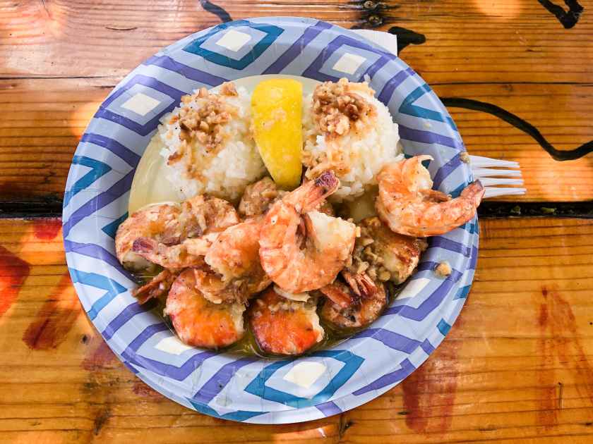 Top down view of famous Hawaiian garlic shrimp and rice plate lunch. Plates with cooked shrimp, lemon, and garlic at Oahu's North Shore.