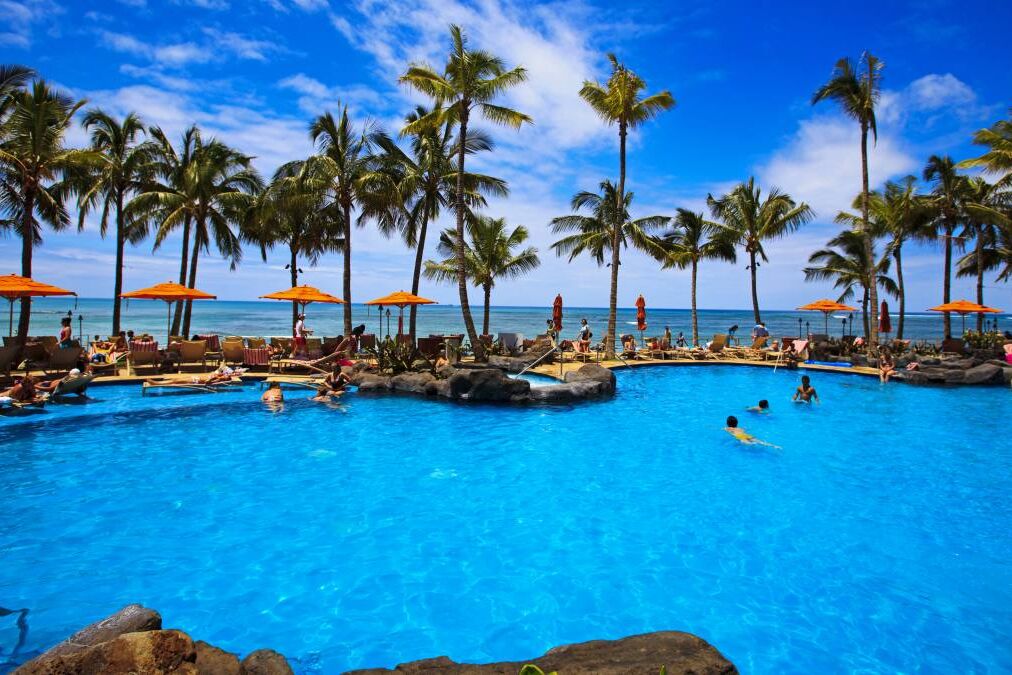 The swimming pool at the Sheraton Waikiki hotel sits at waters edge by the blue Pacific Ocean on Waikiki beach, Hawaii