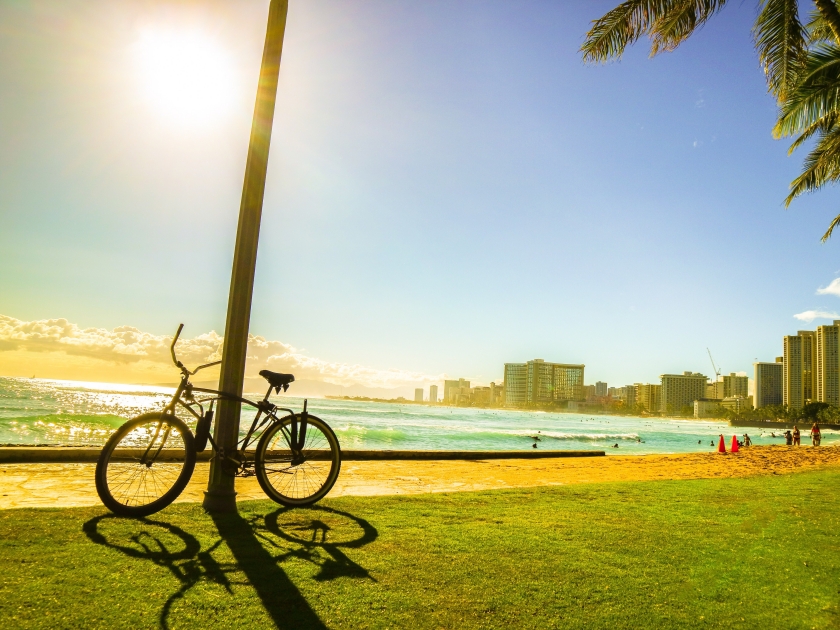 Bicycle on the walkway near the beach with sunset moment and city view in Hawaii silhouette style