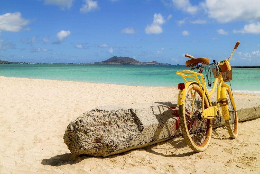 yellow bike leaning next to the concrete pole on the sandy beach