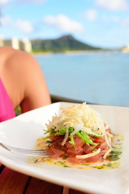 Tuna tartare. Raw ahi, Hawaiian food. Woman eating dish on Waikiki, Oahu, Hawaii.