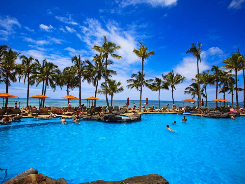The swimming pool at the Sheraton Waikiki hotel sits at waters edge by the blue Pacific Ocean on Waikiki beach, Hawaii