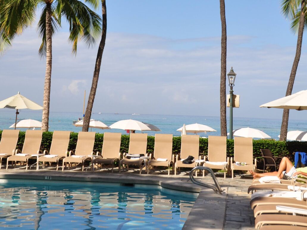 Palm trees and pool in front of ocean at a famous historic hotel - on the island of Oahu along Waikiki beach built in 1901.