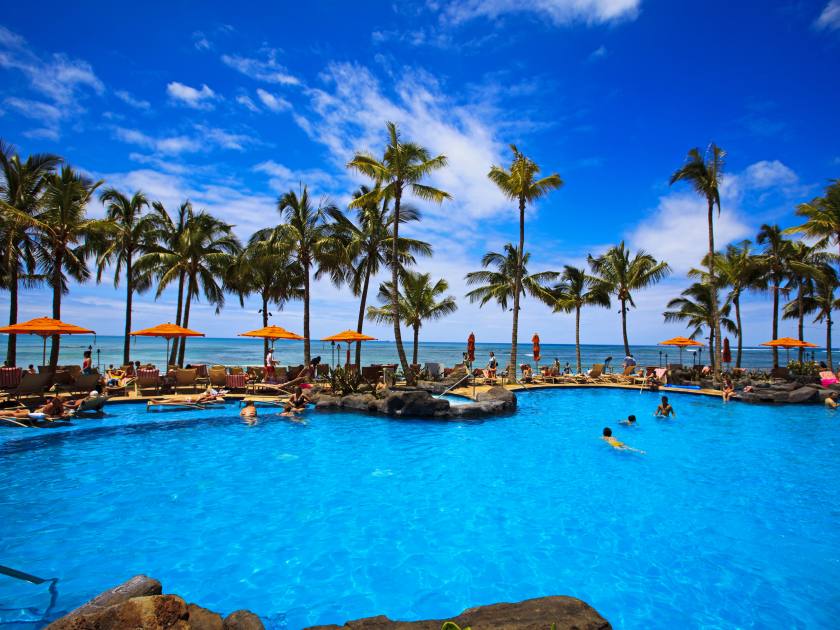 The swimming pool at the Sheraton Waikiki hotel sits at waters edge by the blue Pacific Ocean on Waikiki beach, Hawaii